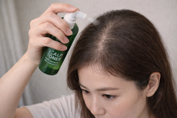 정수리 탈모가 염려되는 여성 두피 토닉을 뿌리고 있는 이미지